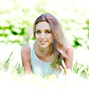 Young woman in blue dress lying on grass