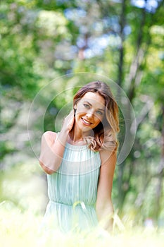 Young woman in blue dress sitting on grass