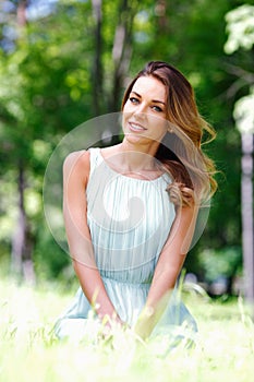 Young woman in blue dress sitting on grass