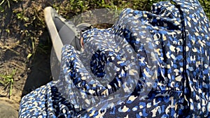 Young woman in blue dress and trainers shoes is sitting and resting outdoors, the hem of her dress is blowing in the breeze