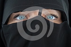 Young woman with blue eyes in black nibe close up. The girl in the burqa. People religious lifestyle concept