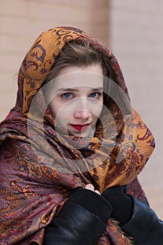 Young woman with blue eyes and red lipstick draping her head and shoulders in multicoloured shaw