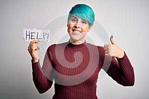 Young woman with blue fashion hair asking for help showing message on paper happy with big smile doing ok sign, thumb up with