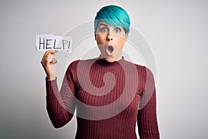Young woman with blue fashion hair asking for help showing message on paper scared in shock with a surprise face, afraid and