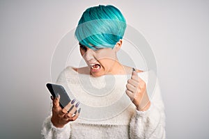 Young woman with blue fashion hair having a conversation using smartphone annoyed and frustrated shouting with anger, crazy and