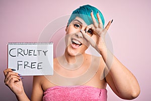 Young woman with blue fashion hair showing cruelty-free cosmetics message with happy face smiling doing ok sign with hand on eye