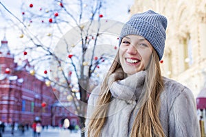 Young woman in a blue knitted hat and gray mink coat