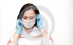 A young woman in blue medical gloves puts a protective mask on her face . A confident girl, a female doctor in a medical