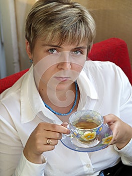 Young woman in blue necklace drinking tea