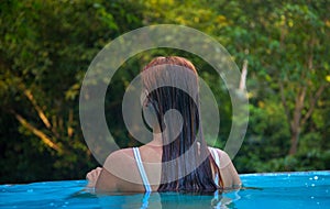 Young woman in blue swimming pool. Girl back in open swimming pool