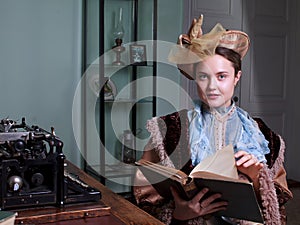 Young woman in blue vintage dress late 19th century reading the book in retro room