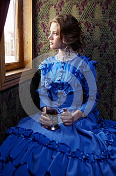 Young woman in blue vintage dress sitting in coupe of retro rai