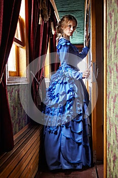 Young woman in blue vintage dress standing in corridor of retro