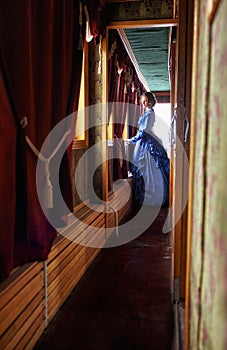 Young woman in blue vintage dress standing in corridor of retro