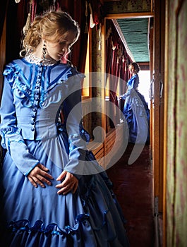 Young woman in blue vintage dress standing in corridor of retro