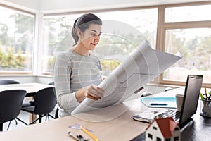 Young woman with blueprint working at home office