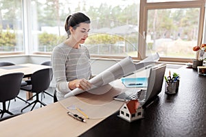 Young woman with blueprint working at home office