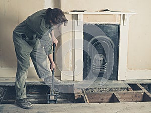 Young woman in boiler suit removing floor boards