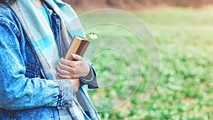 Young woman with book on the walk. Time for reading. Reading book concept. Woman enjoying spring day at nature