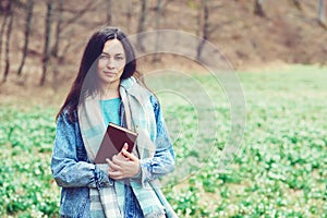 Young woman with book on the walk. Time for reading. Reading book concept. Woman enjoying spring day at nature