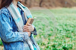 Young woman with book on the walk. Time for reading. Reading book concept. Woman enjoying spring day at nature