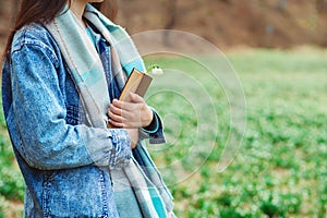 Young woman with book on the walk. Time for reading. Reading book concept. Woman enjoying spring day at nature
