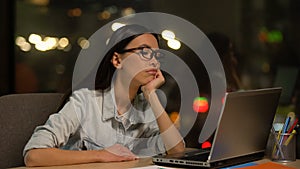 Young woman bored working on laptop in office, lacking motivation, unloved job