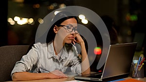 Young woman bored working on laptop in office, lacking motivation, unloved job