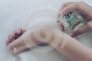 Young woman with bottle of perfume at home, closeup. Happy spraying day with valentine concept