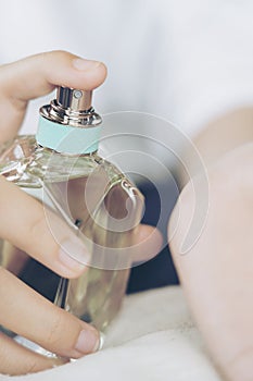 Young woman with bottle of perfume at home, closeup. Happy spraying day with valentine concept