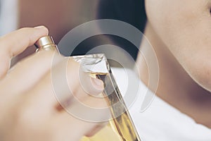 Young woman with bottle of perfume at home, closeup. Happy spraying day with valentine concept