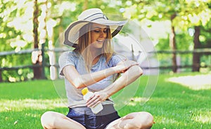 Young woman a bottle of sunblock outside photo