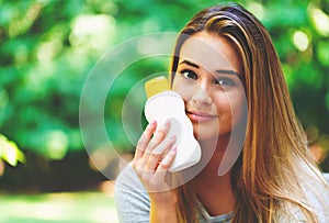 Young woman a bottle of sunblock outside