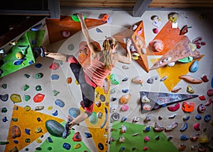 Young woman bouldering on overhanging wall in climbing gym