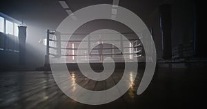 Young Woman Boxer With her Hands Wrapped in Bandage Jumping on Rope in Dark Ring Space a Gym with Smoke.