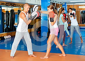 Young woman in boxing gloves punching on focus mitts