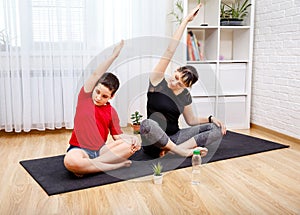 A young woman and a boy in sports clothes are in lotus position .