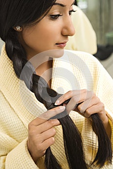 Young woman braiding hair.