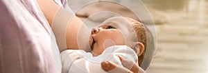 Young woman breast feeding her baby at home, closeup. Banner design