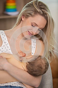 young woman breastfeeding baby at home