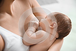 Young woman breastfeeding her baby on blurred background