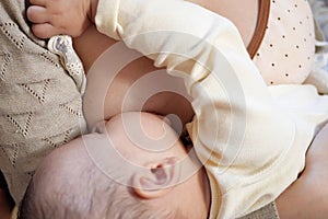 Young woman breastfeeding her baby at home close up