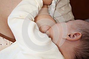 Young woman breastfeeding her baby at home close up