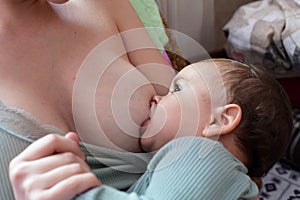 Young woman breastfeeding her baby at home. Milk from mother& x27;s breast is a natural medicine to baby. Mother day