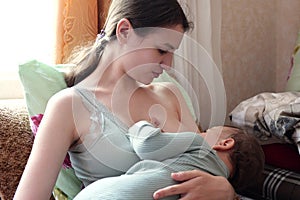 Young woman breastfeeding her baby at home. Milk from mother& x27;s breast is a natural medicine to baby. Mother day