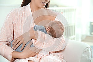 Young woman breastfeeding her baby in nursery