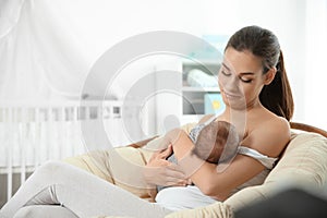 Young woman breastfeeding her baby in nursery