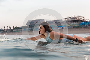 Young woman in bright bikini surfing on a board in ocean