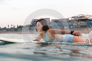 Young woman in bright bikini surfing on a board in ocean