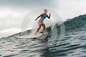 Young woman in bright bikini surfing on a board in ocean